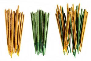 Groups of yellow and green incense sticks on white background.
