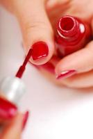 Woman applying red  nail polish photo