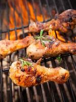 Chicken drumsticks cooking in open fire grilling pit