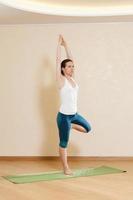 Caucasian woman is practicing yoga at studio (vrikshasana) photo