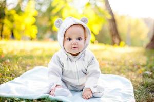 Cute caucasian baby boy in park looks at camera