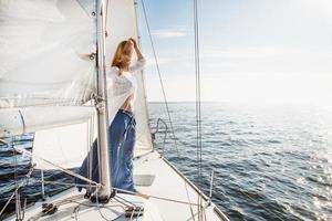 joven mujer caucásica en un velero mirando el horizonte foto
