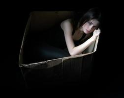 Concept of homeless. Upset girl in cardboard box