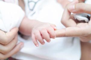 Little tiny baby hand holding mother finger photo