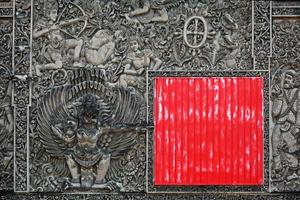 Ancient Balinese stone carving background with the red square shield photo