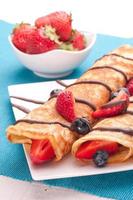 Pancakes served with strawberries, blueberries and chocolate on