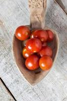 tomates cherry en una cuchara sobre fondo de madera foto