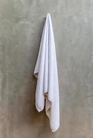 White towel is hanging on a hanger with concrete wall