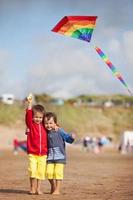 Two children playing with a kite on the beach