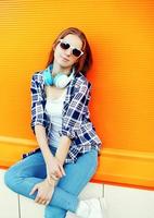 Pretty girl in sunglasses and headphones against the colorful or photo