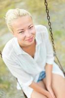 Young blonde woman sitting on the swing photo