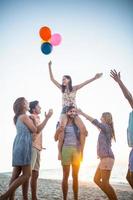 Happy friends dancing on the sand with balloon photo