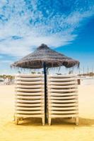 Reed umbrella and sunbeds on the beach photo