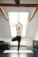 Young woman practicing yoga in living room photo