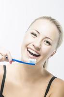 sonriente mujer caucásica con cepillo de dientes contra blanco foto