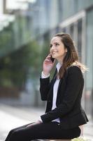 Young Caucasian businesswoman standing outside using mobile phon
