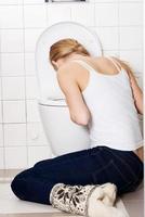 joven mujer caucásica está vomitando en el baño. foto