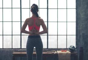 Mujer con las manos juntas detrás de la espalda en pose de yoga foto