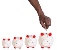 Male hand putting a coin into a piggy bank photo
