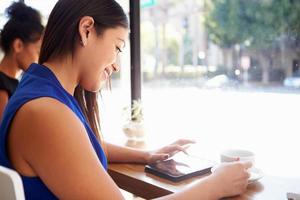 Businesswoman Using Digital Tablet In Coffee Shop