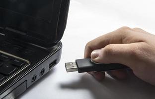 Insertar a mano la memoria USB a la computadora portátil foto