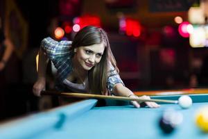 Young beautiful young lady aiming to take the snooker shot photo