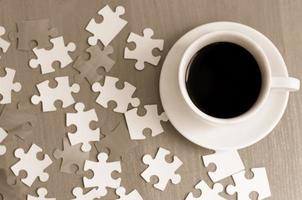 taza de café y piezas de rompecabezas en la mesa