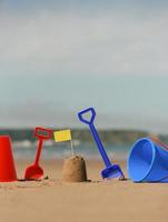 Beach, sea with buckets spades sandcastle and yellow flag