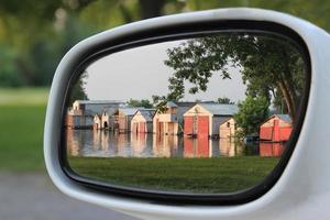 Reflection in Side Mirror of Car, of Boat Houses Reflected in Water photo