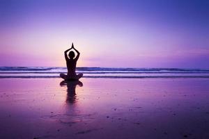 mujer practicando yoga en la playa foto
