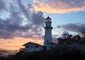 Lighthouse amidst sunset sky