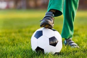 Blond boy of 4 playing soccer with football onl field photo