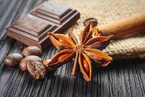 Chocolate bar and spices on wooden table photo