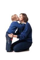 joven madre besando amorosamente a su pequeño hijo. aislado en blanco