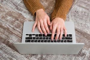 Top view of female hands typing on laptop keyboard
