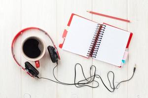auriculares, taza de café y bloc de notas en el escritorio foto