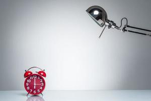 lighting up red alarm clock with desk lamp photo