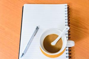 Notebook and coffee on wooden background