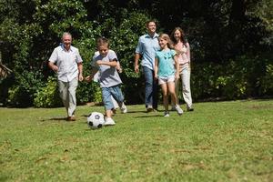 feliz familia multigeneración jugando al fútbol
