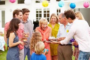 Familia multigeneración celebrando cumpleaños en jardín foto