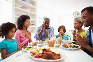 Familia afroamericana de múltiples generaciones rezando en casa foto