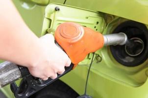 Women hold Fuel nozzle to car at gas station