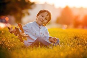 Cute boy, playing with airplane on sunset in the park photo