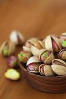 Pistachios with and without shell in wooden bowl