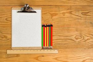 Blank clipboard with paper and colorful pencils on desktop