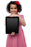 sonriente niña afroamericana que presenta tablet pc foto
