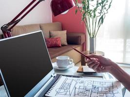 Diseñador trabajando con laptop y dibujo arquitectónico en un espacio de trabajo moderno