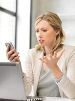 mujer confundida con teléfono celular en la oficina foto