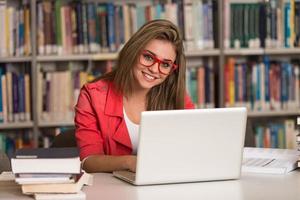 joven estudiante usando su computadora portátil en una biblioteca foto