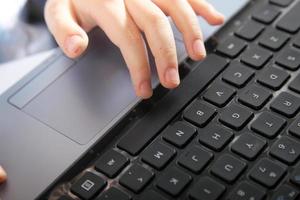 boy's hand typing on laptop keyboard